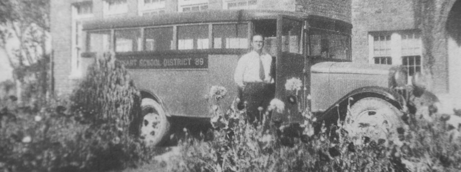 Historic photo of old Dysart bus with person standing next to it.
