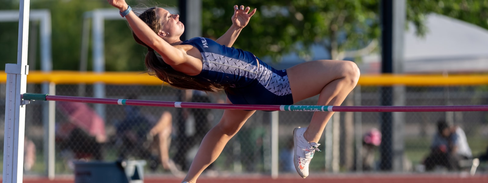 Girl performing athletic high jump for track and field event.
