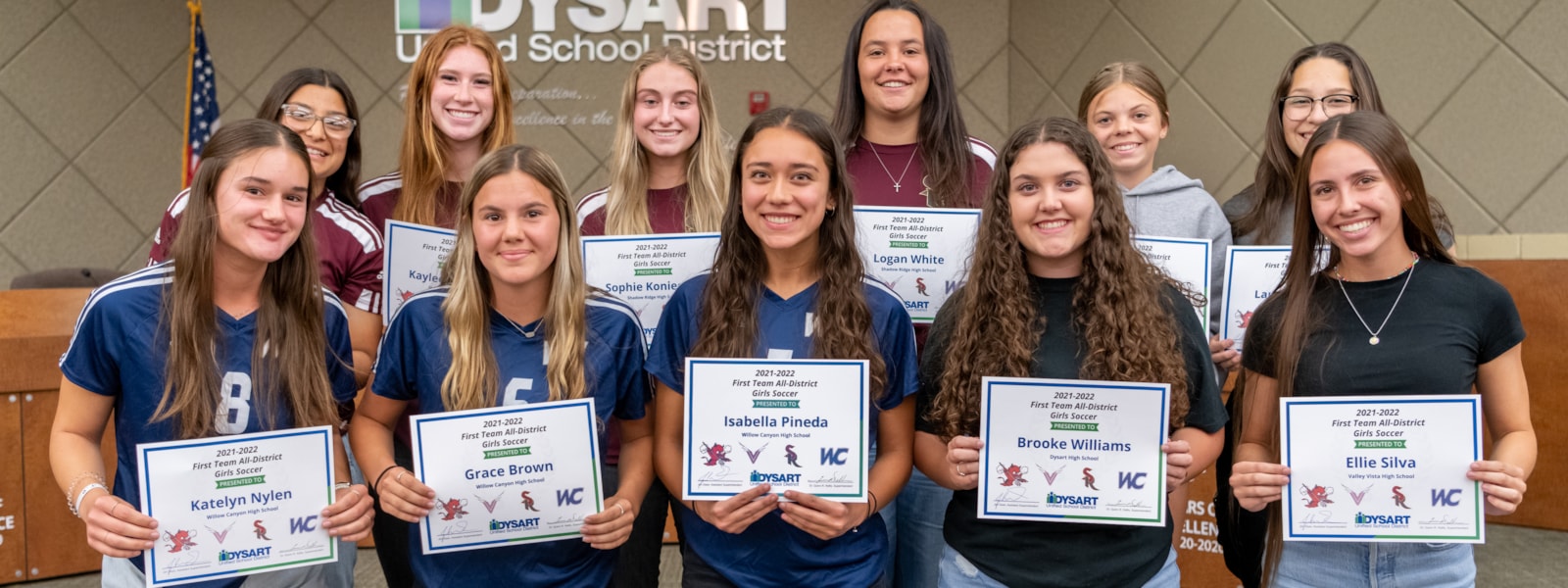 Girls soccer players pose with certificates