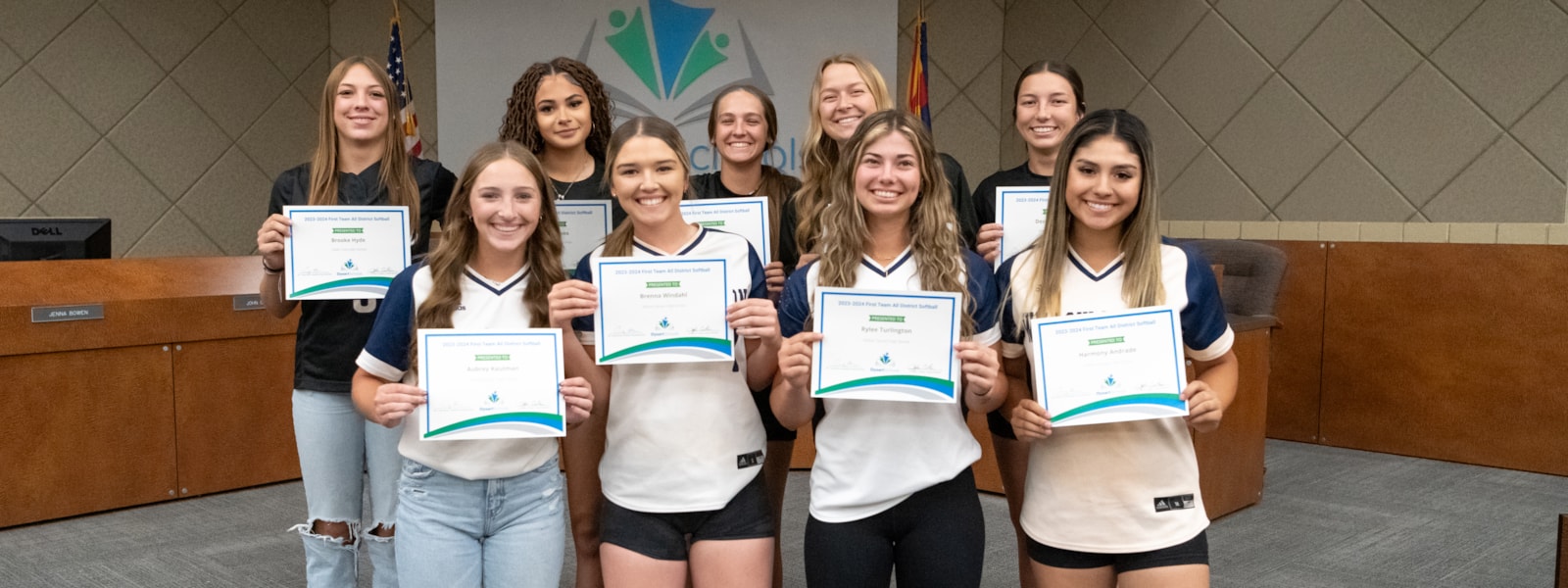 Softball players holding their certificates and smiling for the camera