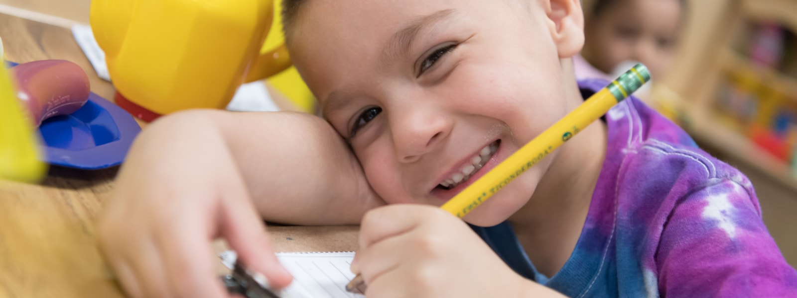 Preschool student smiling while writing