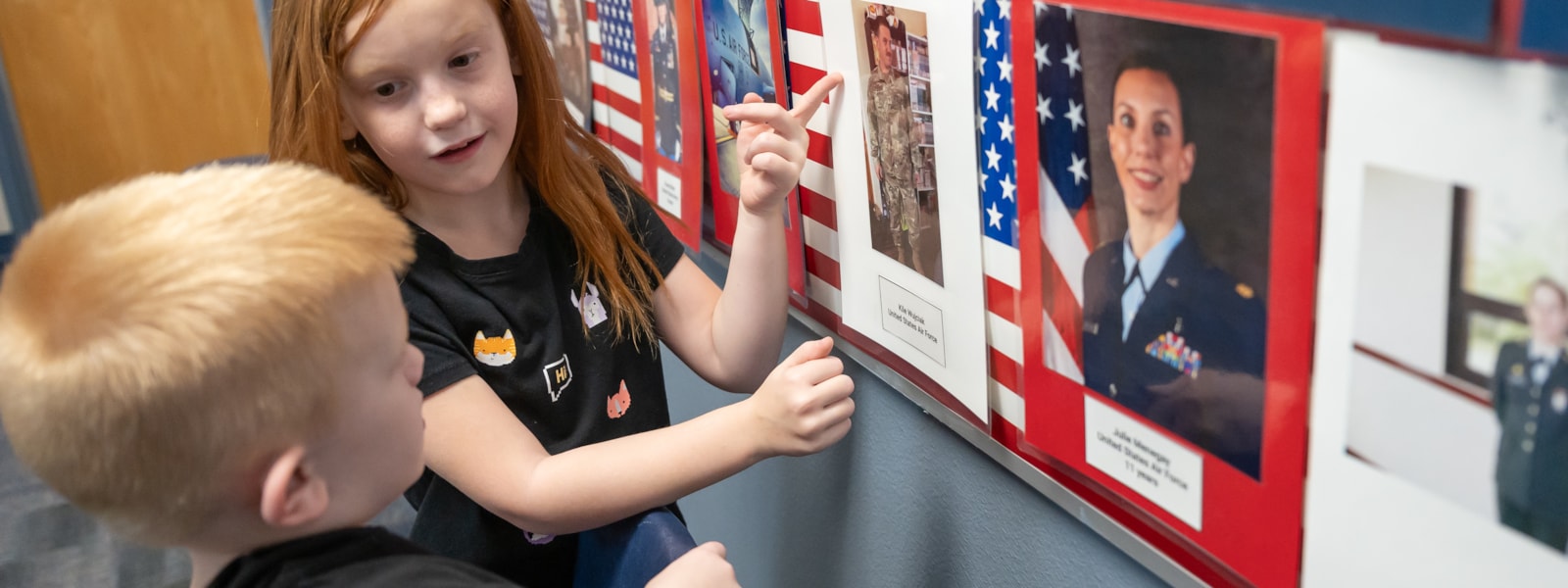 2 students pointing at Honor Wall in Deployment Room
