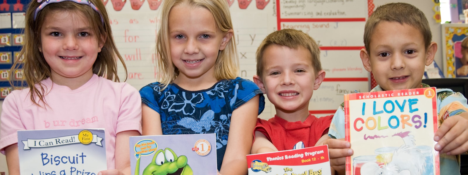 Smiling kids holding a book.