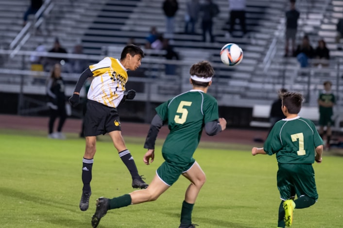 Middle school student heading soccer ball during championship game.