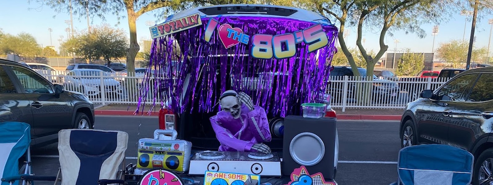 Festival event showing a skeleton disk jockey, record player, blow up boom box/radio and fake speakers with "I Love the 80s" hanging decoration.