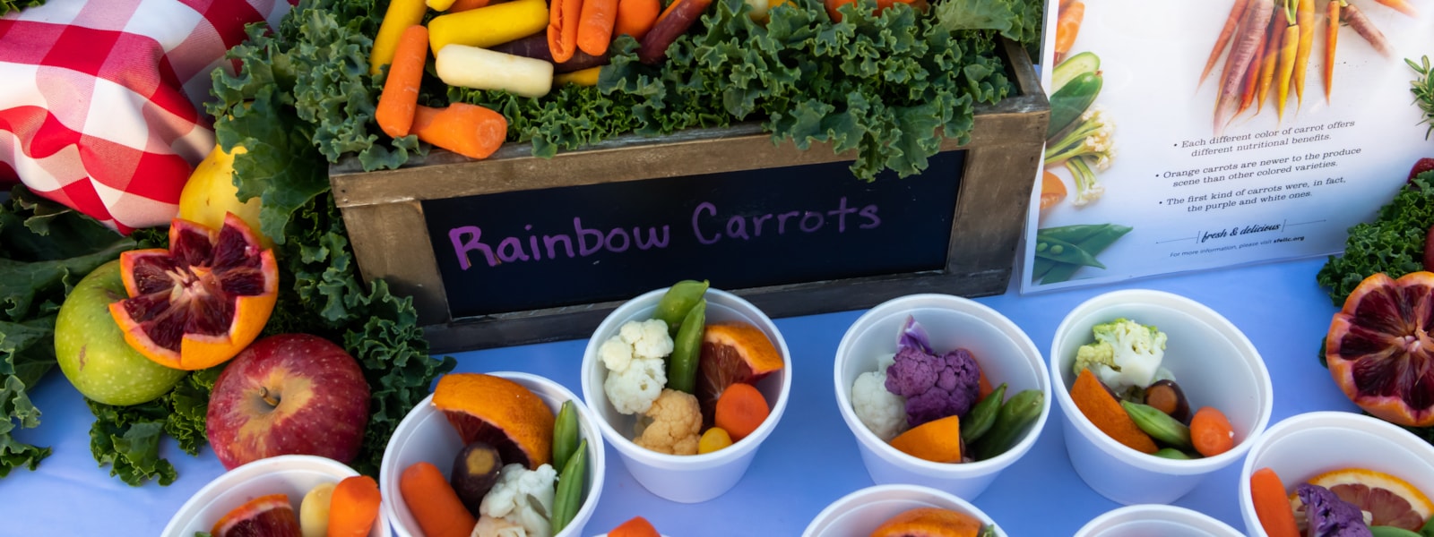 fruits and veggies on a table with a box of rainbow carrots
