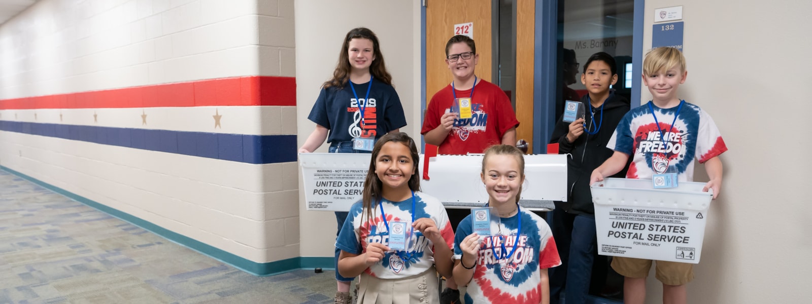 Students pose with their post office badges and mail bins in the Freedom Traditional Academy hallway.