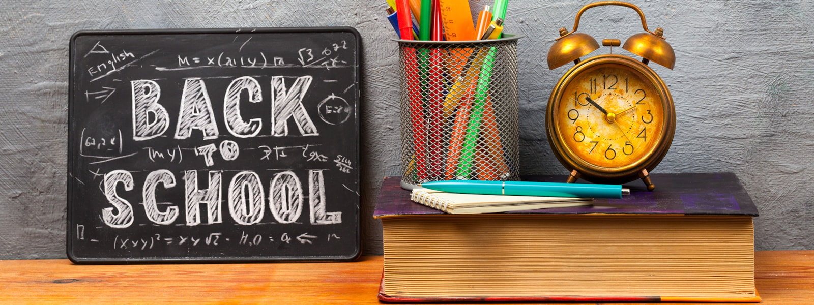 back to school sign with pencils, clock, pen, pad of paper, and a book. 