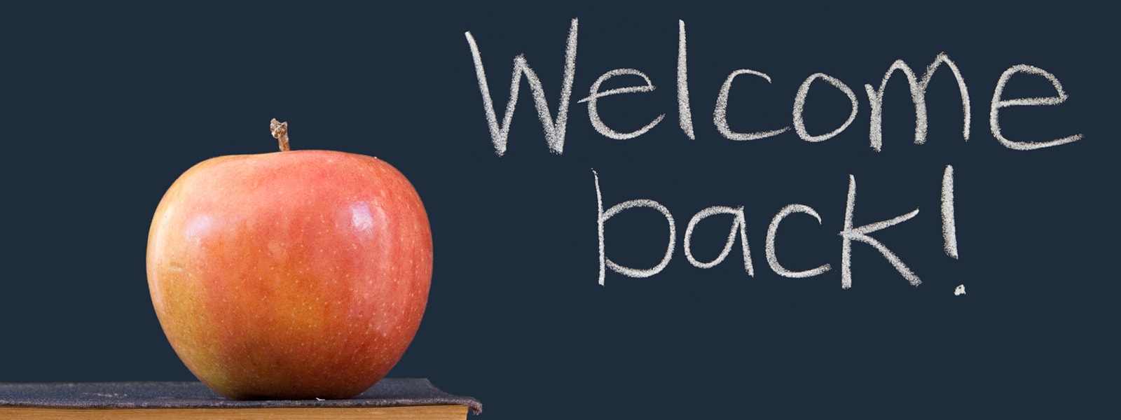 welcome back sign with apple on a book.