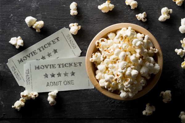 a couple of movie tickets with a bucket of popcorn 