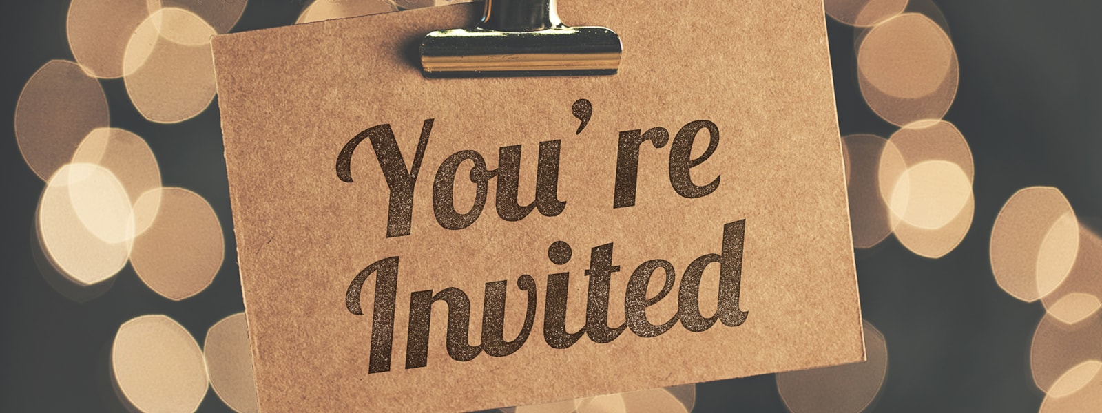 A note with the words you're invited handing from a clip