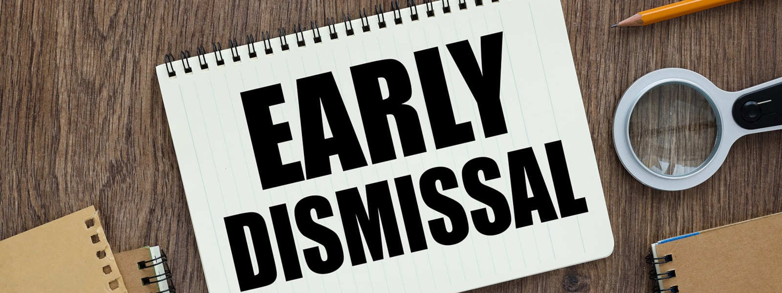 'early dismissal' on a notebook with magnifying glass and pencil next to it