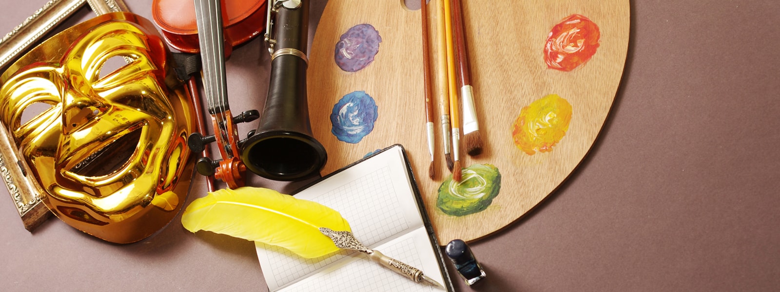 the arts symbols: drama mask, band instruments, writing journal and artist's palette