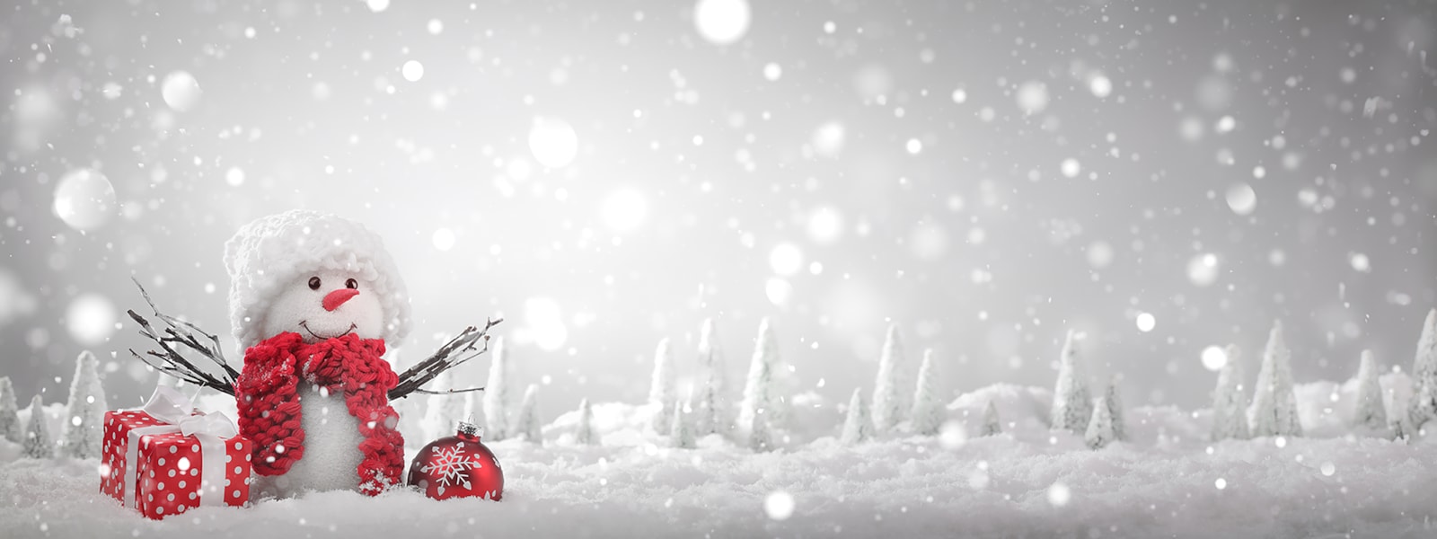 a snowman with red scarf on a snowy backdrop with a red present and red ornament next to it.