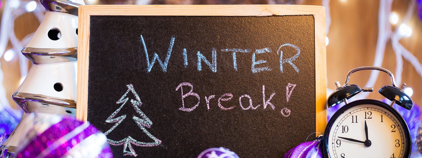 Winter Break written on a chalkboard with purple ornaments and alarm clock surrounding it
