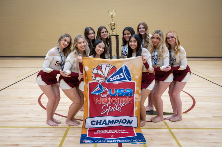 Pom members posing with trophy and banner