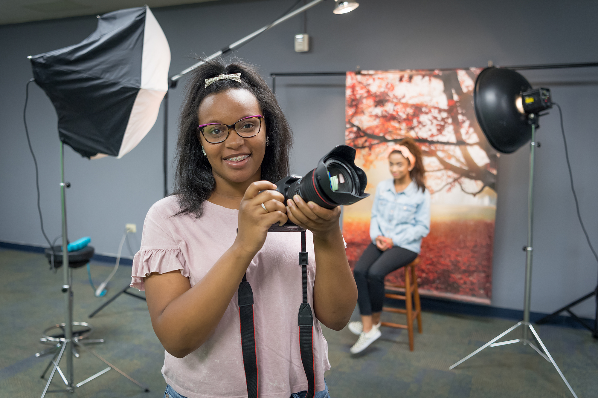 Student holding camera in camera studio with lights