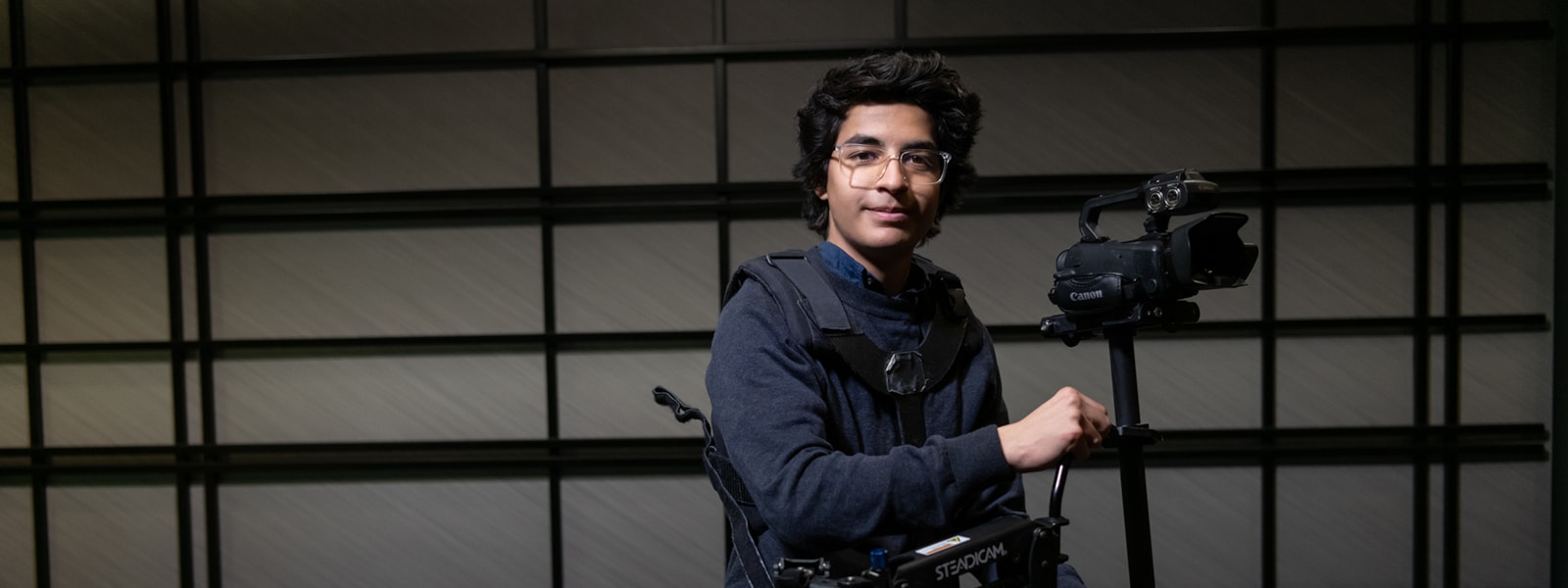Student holding camera in a film and television studio.