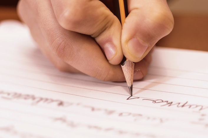 Student writing on a sheet of paper in cursive