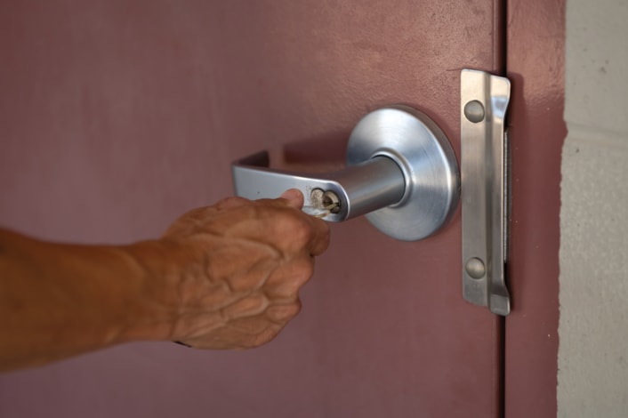 Hand with key locking a door.