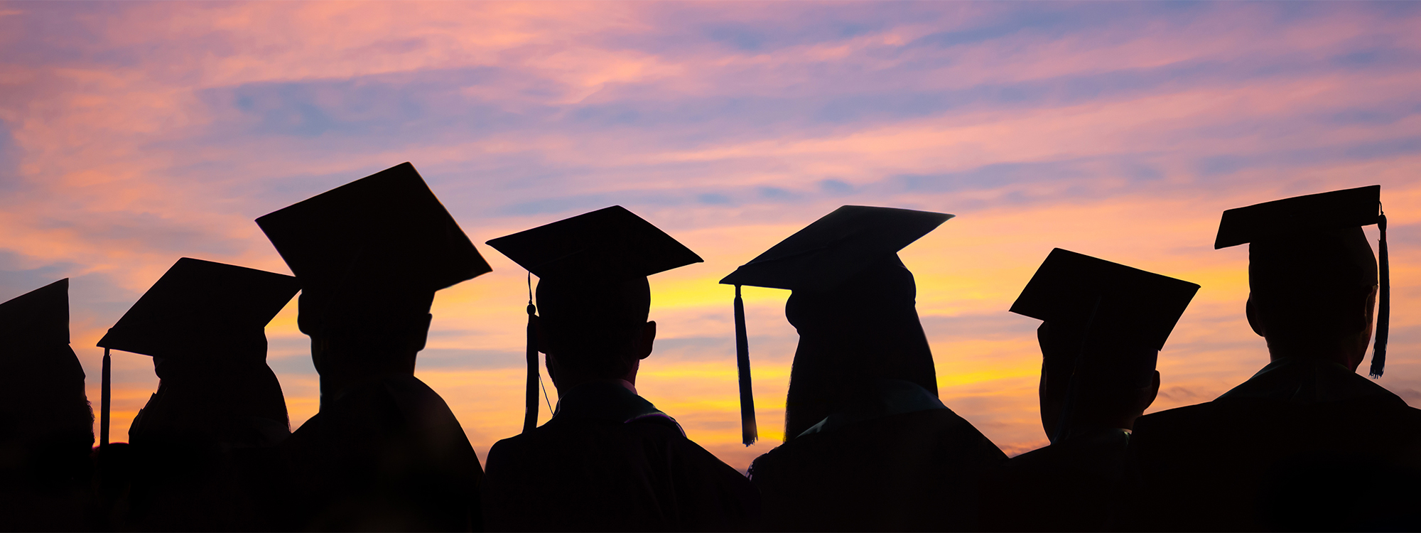 graduates against a setting sun sky