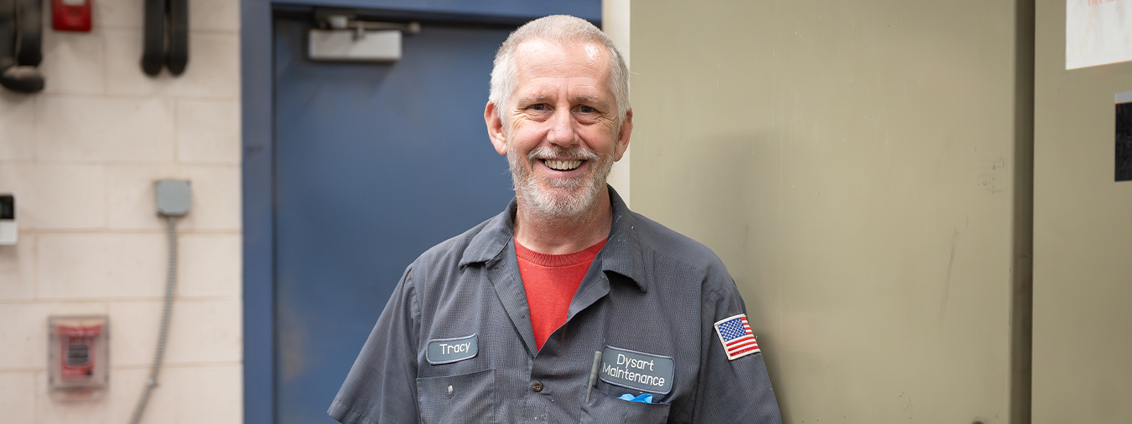 Plant Manager wearing a work shirt with Dysart Maintenance patch standing in front of heavy equipment