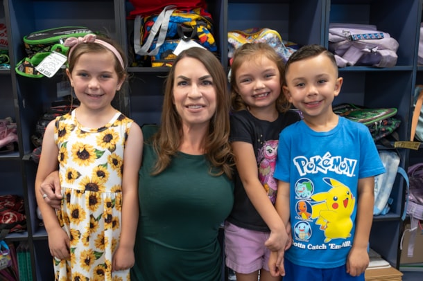 teacher in a green dress with three students smiling for the camera