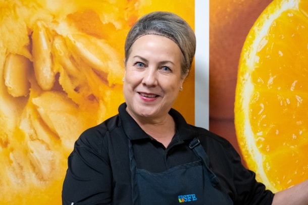 Cafeteria worker posing in front of a brightly colored wall 