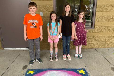 students posing at festival of the arts with a chalk art creation