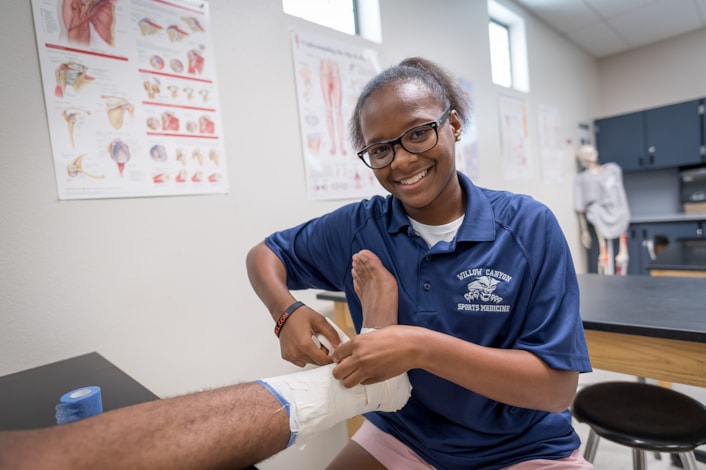 student wrapping ankle with sports medicine tape