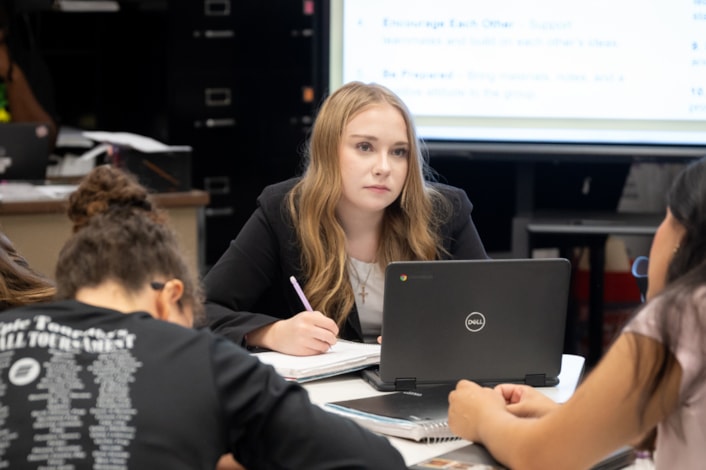 high school student working on laptop in a classroom