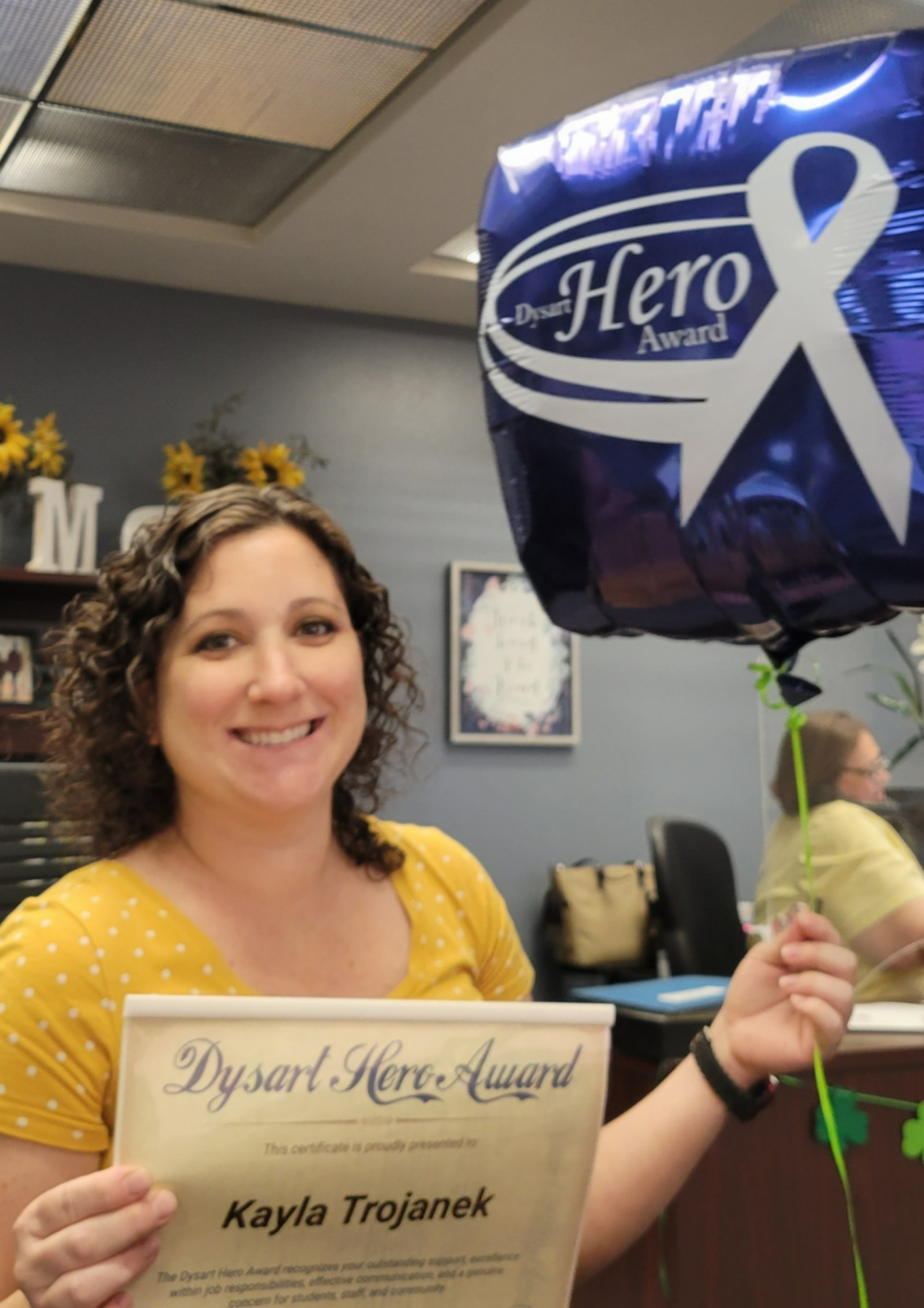 Ms Trojanek holding certificate and blue Hero balloon