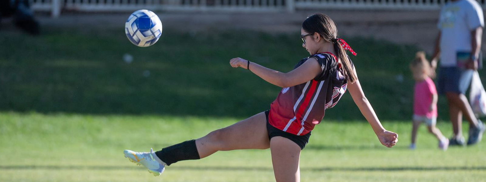 Female soccer player kicking a soccer ball into the air