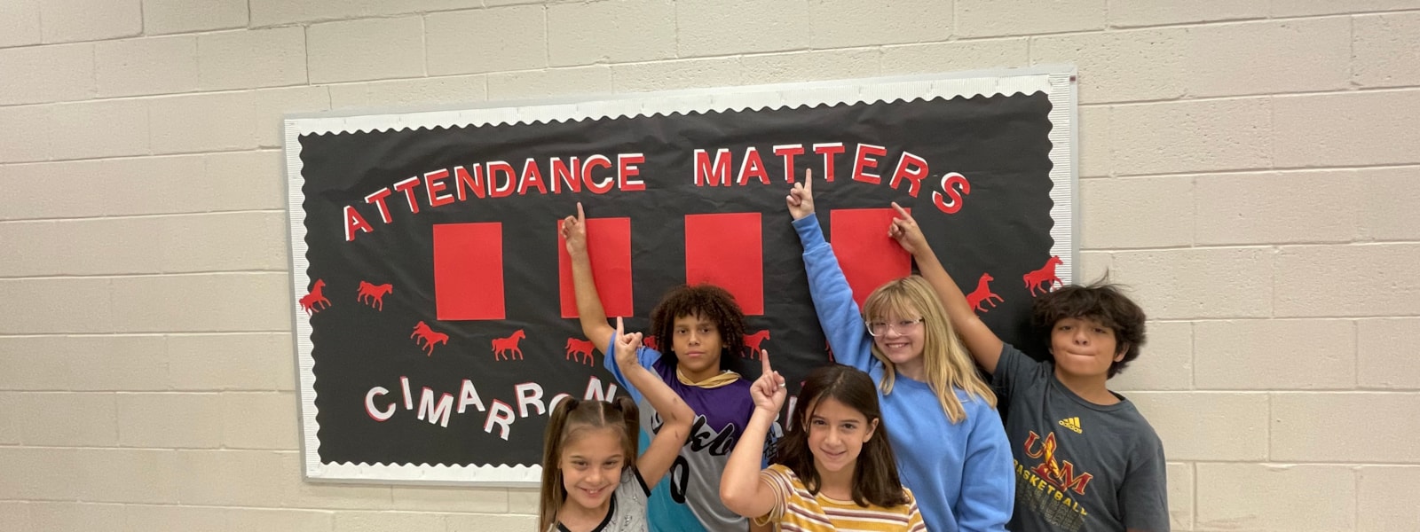 Students pointing at "Attendance Matters" board