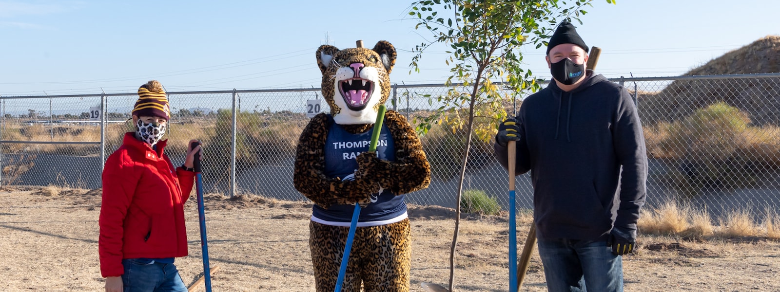 The principal of Thompson Ranch, Dr. Kellis, and the mascot pose while planting trees.