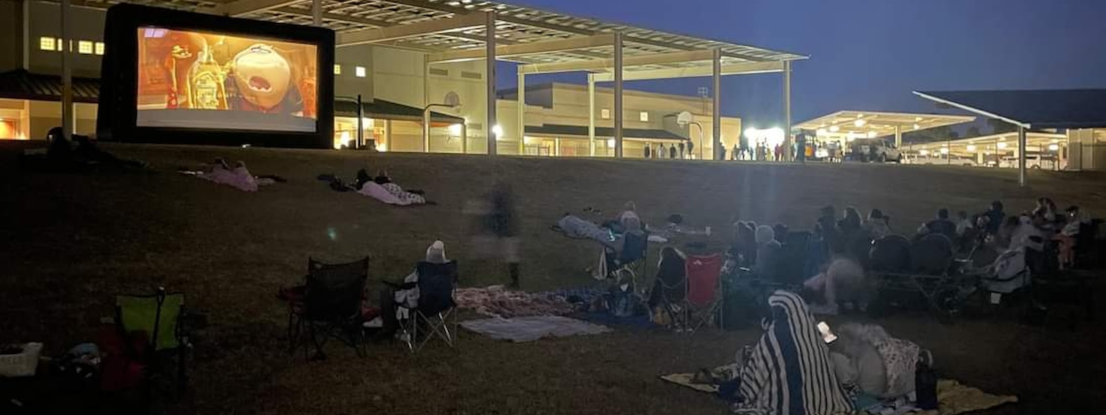families sitting on the lawn watching a movie