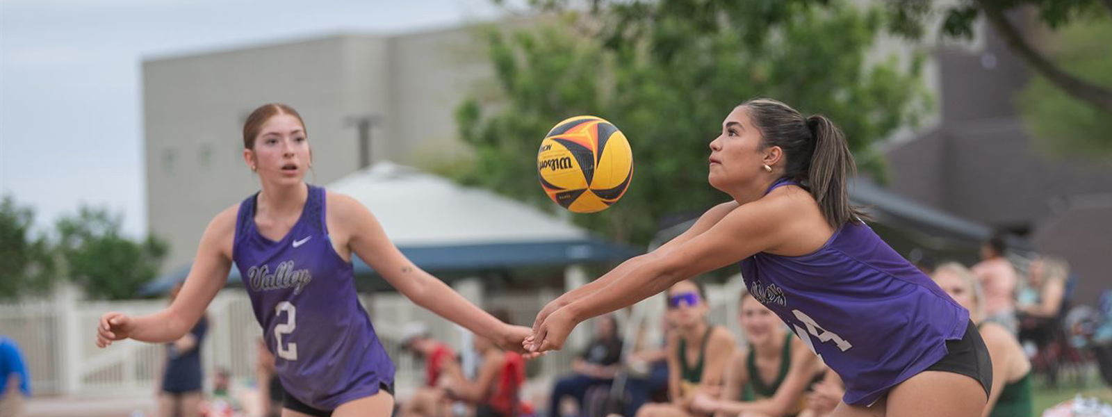 Beach volleyball player bumping the ball with a teammate in the background