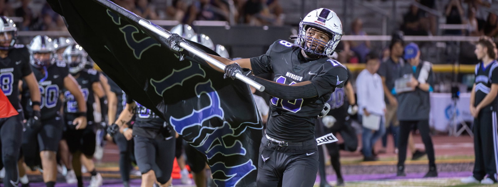 Football player running onto the field with the Valley Vista flag