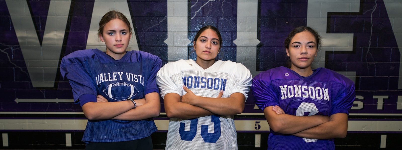 Sara Lowry, Mackenzie Goodrich, and Vanezza Valdez pose for a photo in their football uniforms for Valley Vista High School.