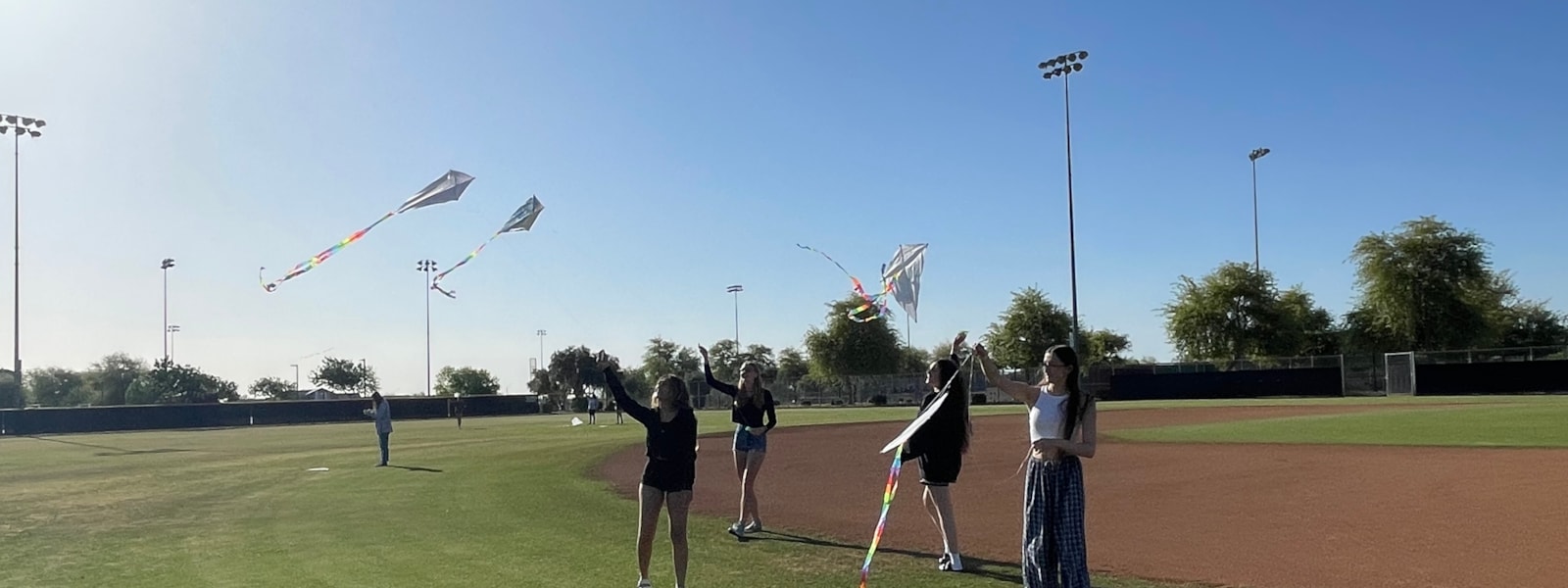 Students on grassy field flying kites