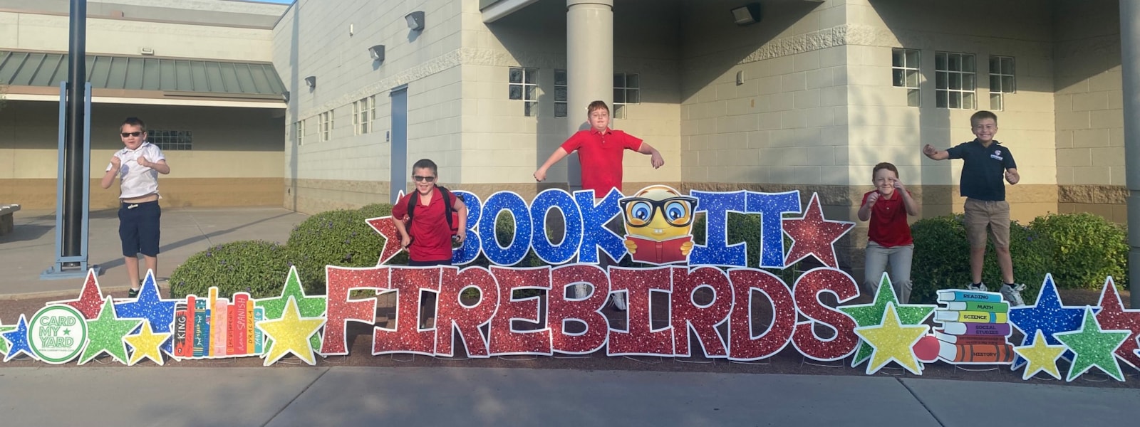 Students standing by a sign that says Book It Firebirds 