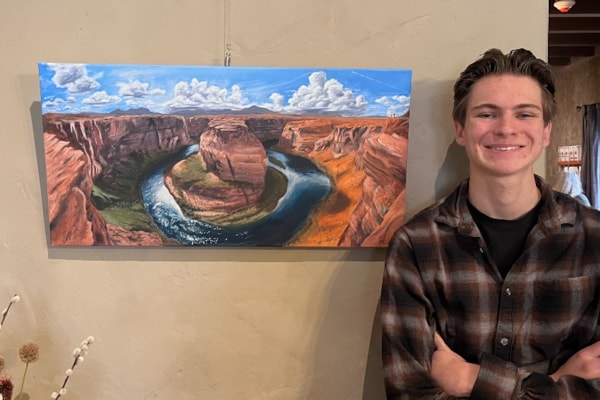 Student standing next to his painting 