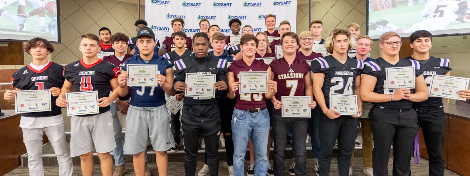 Football players pose for a picture with their all-district awards.